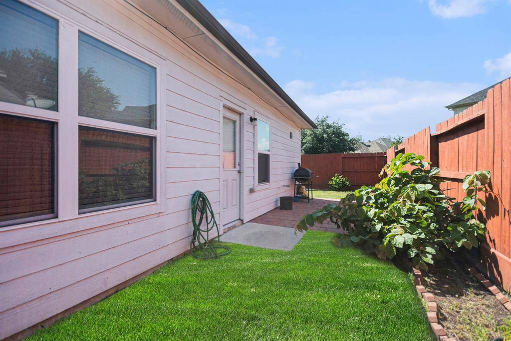 Charming backyard retreat with lush greenery, privacy fencing, and a cozy patio for outdoor enjoyment.