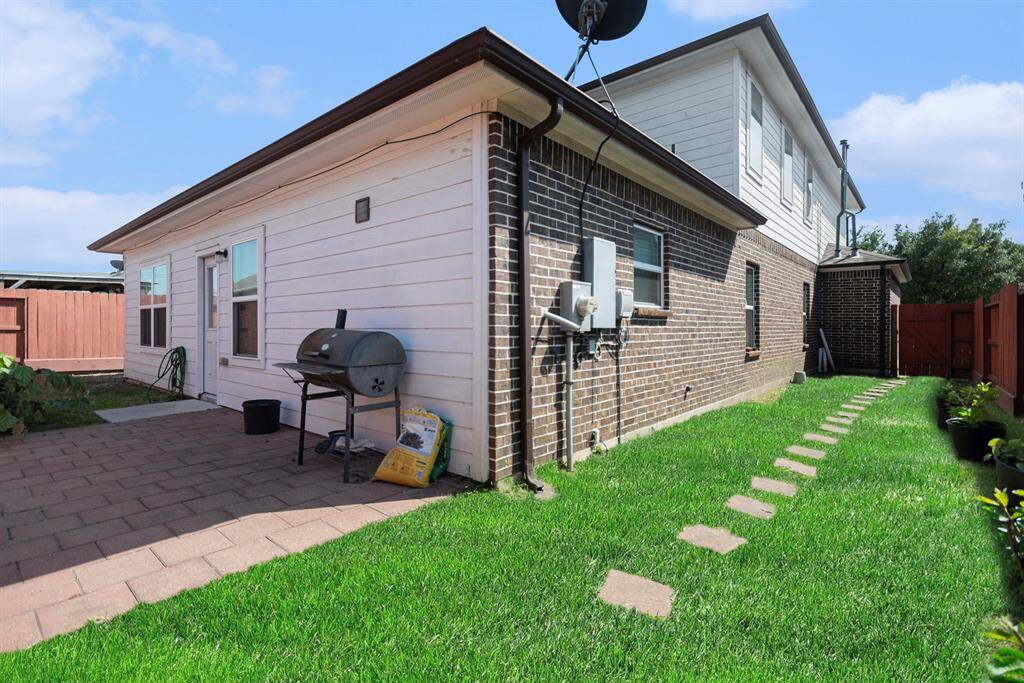 Charming backyard featuring a paved patio, perfect for outdoor gatherings, and a lush lawn with a convenient stone path.