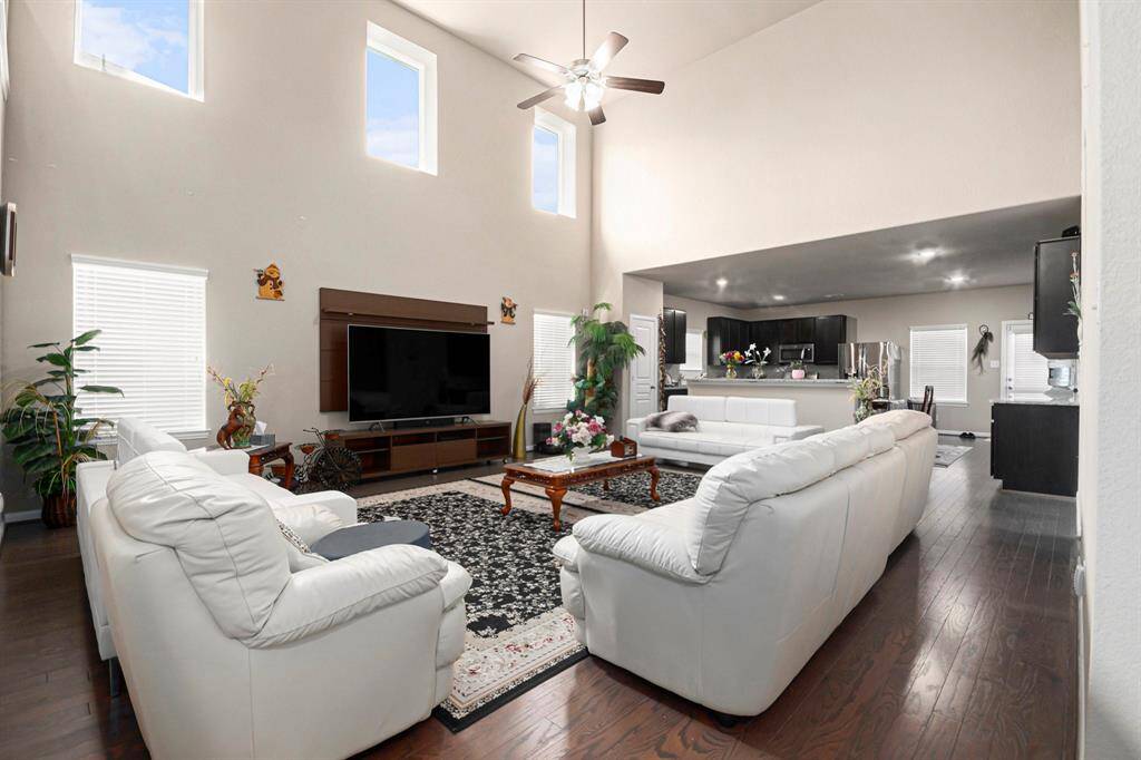 Spacious living room with high ceilings, abundant natural light, and elegant hardwood floors, seamlessly flowing into the modern kitchen—perfect for entertaining.