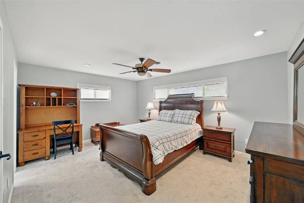 THE PRIMARY BEDROOM FEATURES CEILING FAN AND PLUSH CARPET.