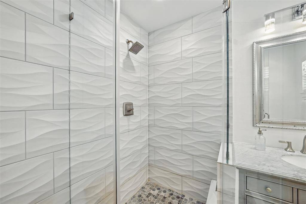 A CLOSE-UP OF THE HUGE WALK-IN SHOWER WITH RAIN SHOWER HEAD.