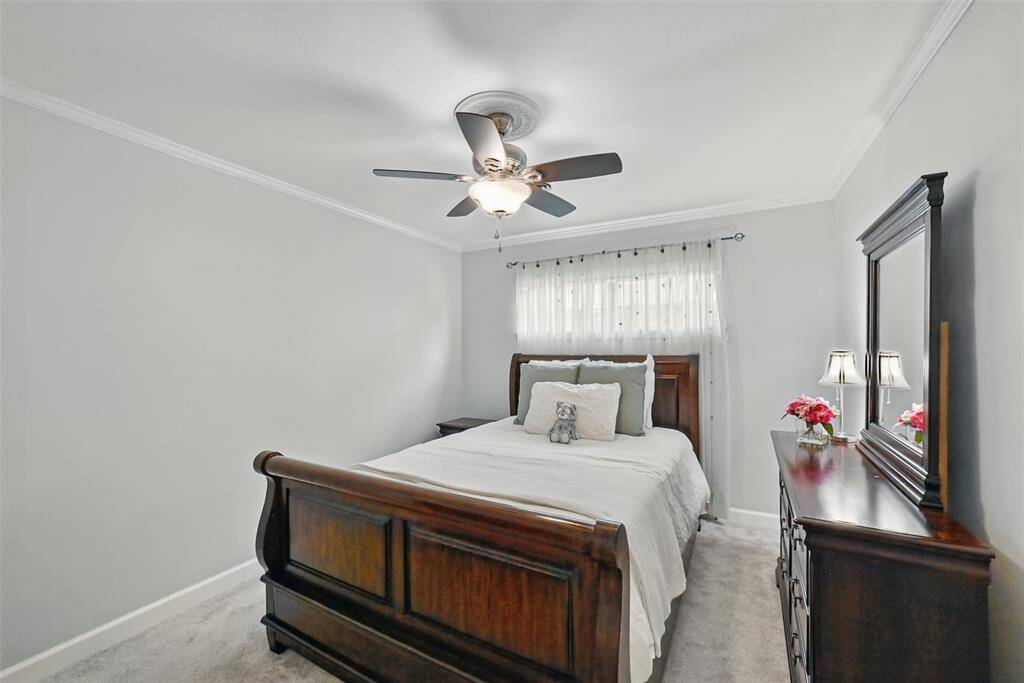 SECONDARY BEDROOM WITH CROWN MOLDING AND CEILING FAN.