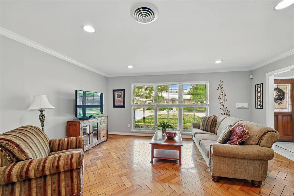 THE HALLWAY OPENS UP TO THE FORMAL LIVING AREA WITH HERRINGBONE WOOD FLOORING, CROWN MOLDING AND LARGE PICTURE WINDOW ALLOWING IN PLENTY OF NATURAL LIGHT.