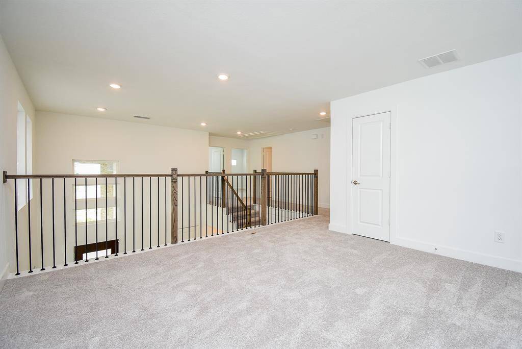 Spacious game room with plush carpeting and modern lighting, perfect for entertainment and relaxation.