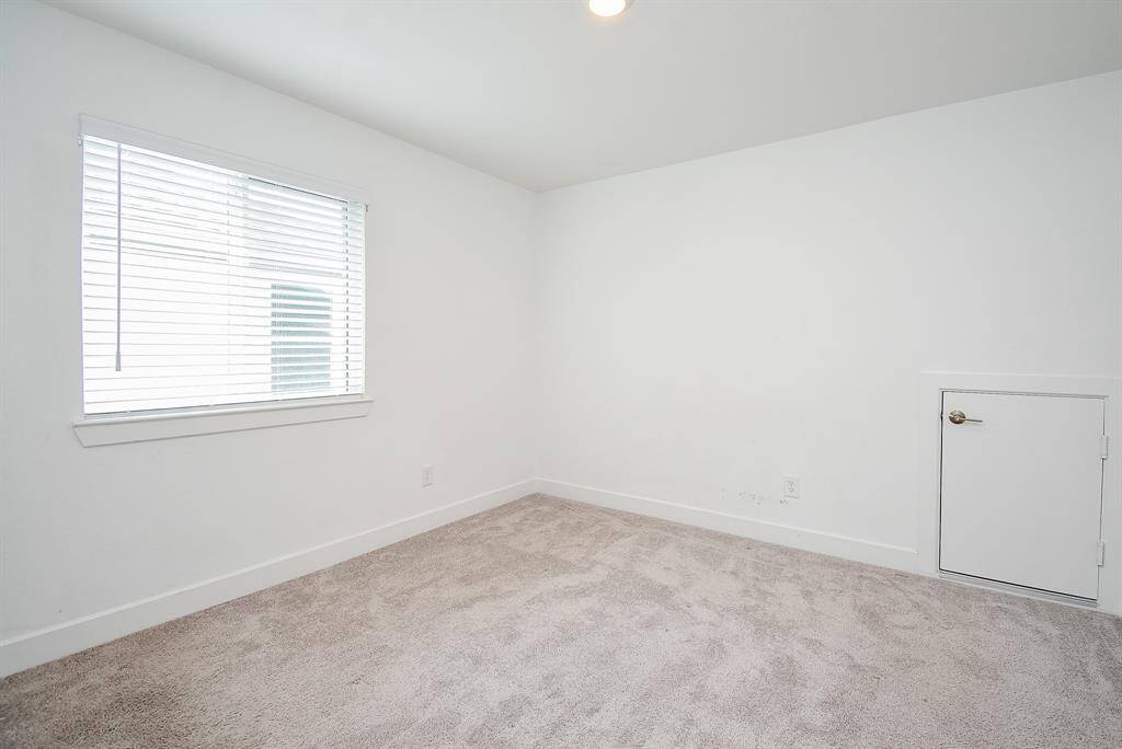 Cozy secondary bedroom with ample natural light and plush carpeting, perfect for guests or a home office.