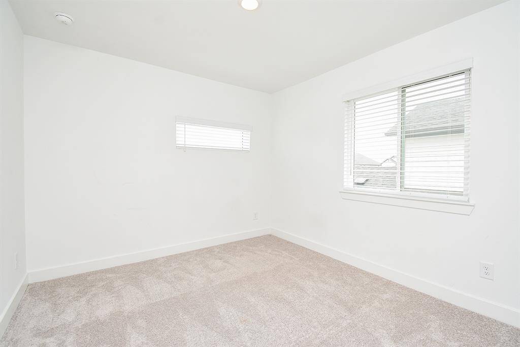 Bright and airy secondary bedroom with soft carpeting and ample natural light. Perfect for guests or a home office.