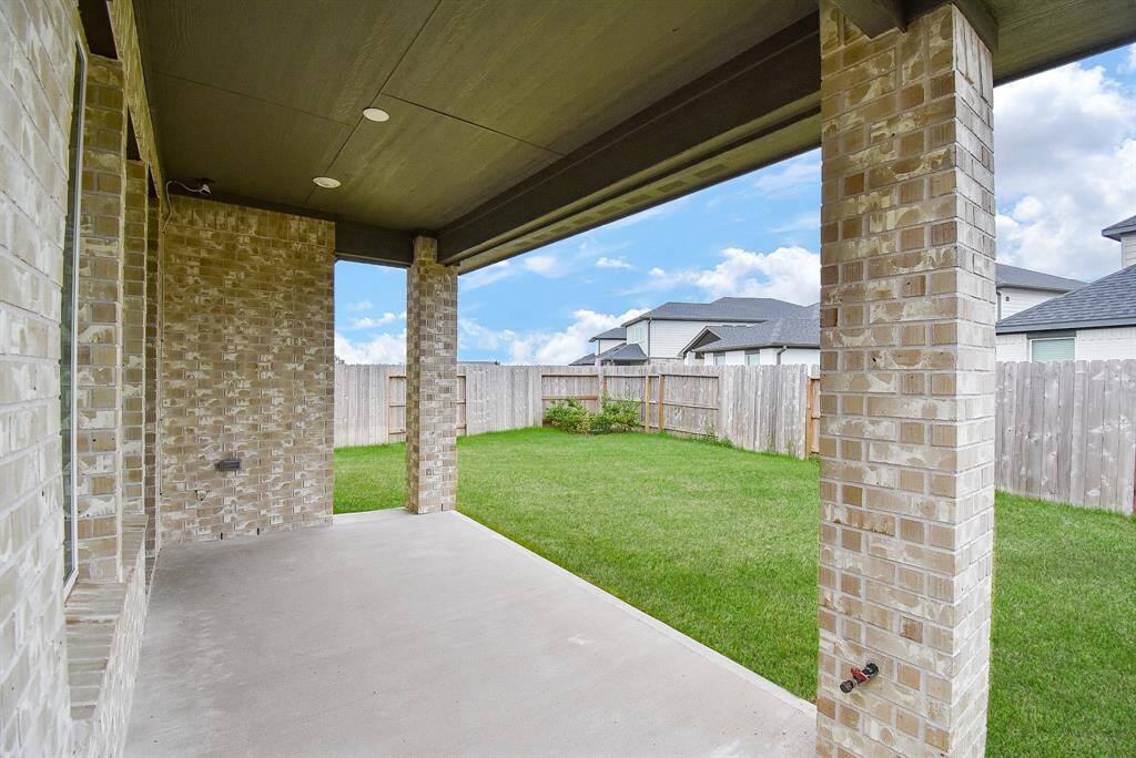 This photo showcases a covered patio with brick columns, opening to a well-maintained, fenced backyard, offering a private outdoor space perfect for relaxation or entertaining.