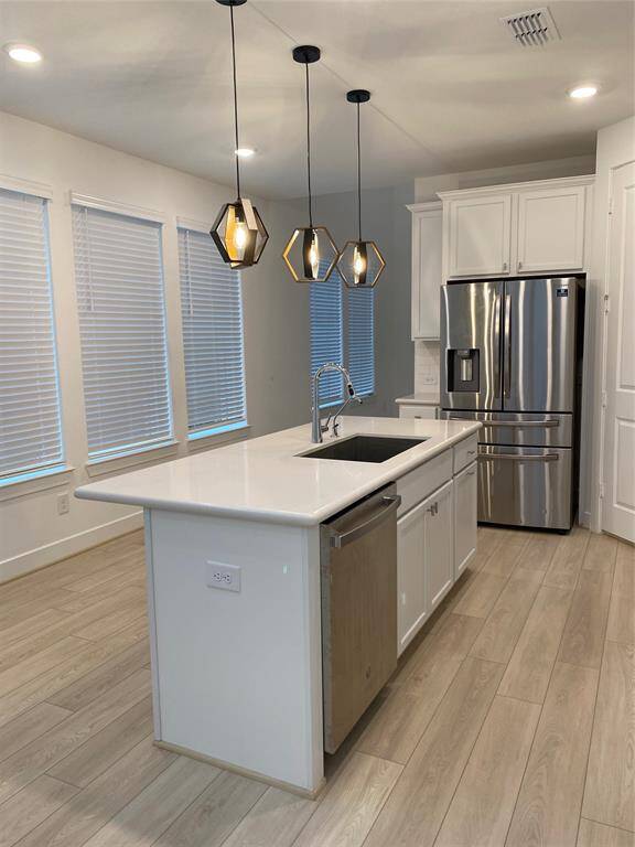 Bright, modern kitchen featuring a large island with sink, stainless steel appliances, and ample natural light from multiple windows.