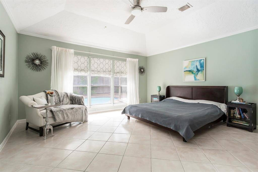 Wake up to peaceful pool views in this spacious primary suite, where soft natural light, a soaring ceiling, and cool tile flooring create a calm and relaxing retreat. With plenty of room to stretch out and unwind, this serene space is the perfect spot to begin and end your day.