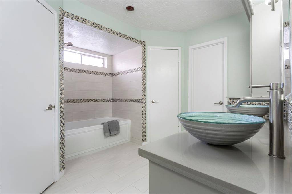 Unwind in style with this beautifully tiled tub and shower combination, framed by striking mosaic accents and filled with soft natural light from the transom window above. Whether it’s a quick rinse or a long soak, this space brings spa-like comfort to your daily routine.