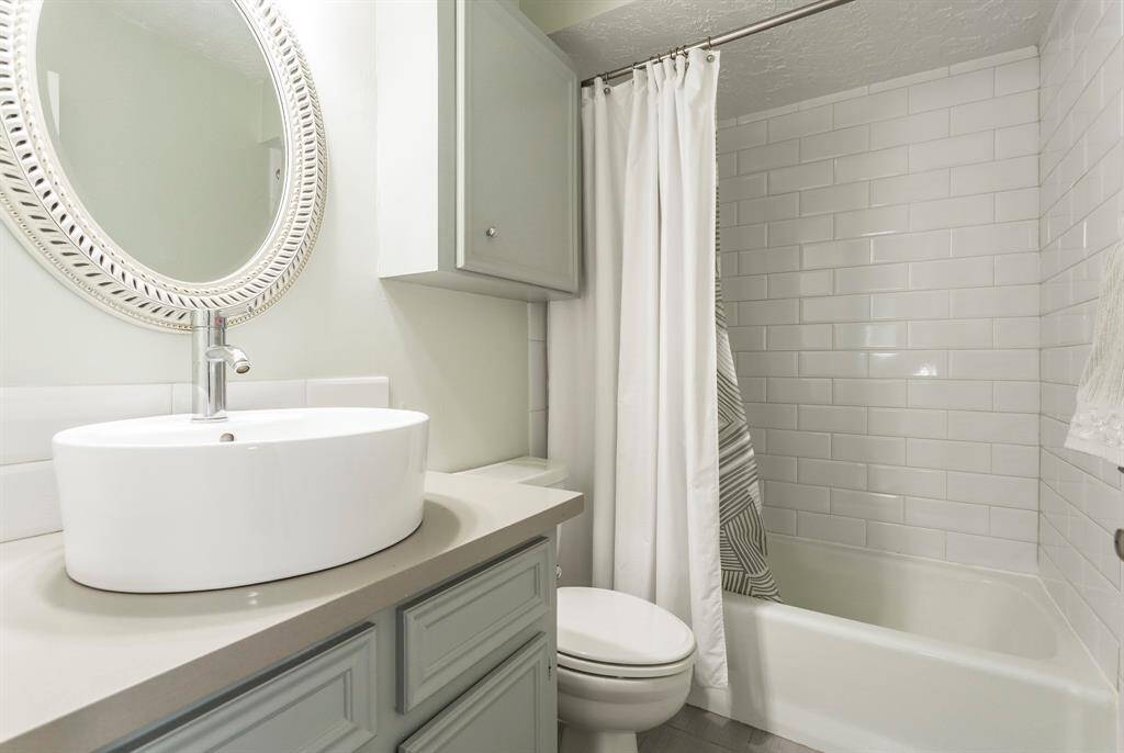 This stylish full bathroom features a sleek vessel sink, quartz countertop, and classic white subway tile in the tub/shower combo. With its fresh, modern finishes and thoughtful storage, it’s perfectly equipped for guests or everyday use.