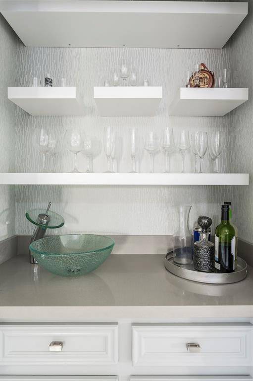 Cheers to easy entertaining! This chic wet bar just off the family room is perfect for mixing cocktails, pouring a glass of wine, or serving up snacks during game night or weekend gatherings. A sleek vessel bowl sink and modern faucet add a stylish, functional touch to this well-designed space.