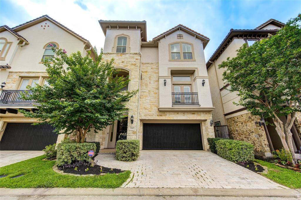 This elegant, three-story townhouse features a stone facade and modern architecture. It includes a spacious two-car garage, a small front yard with well-maintained landscaping, and charming balconies, offering a sophisticated urban living experience.