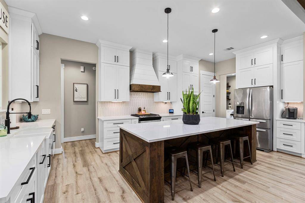 Shiplap and wood molding hosting the vent and plenty of cabinet space all around this kitchen space.