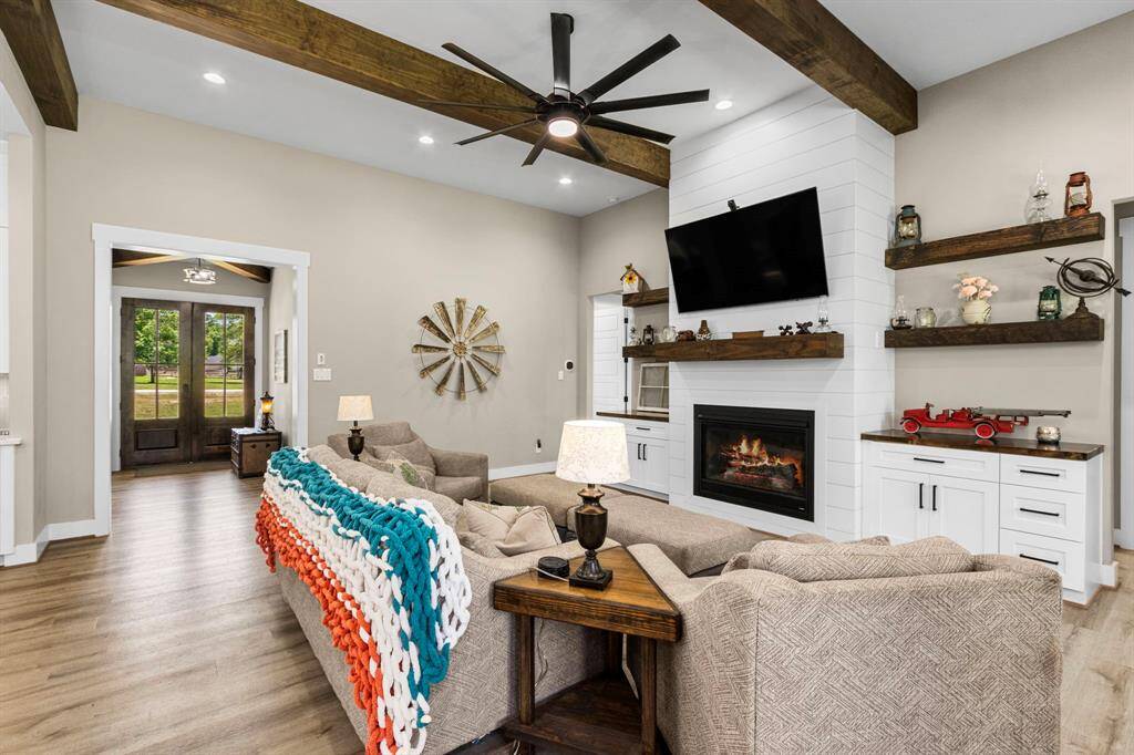 Beautiful beams warming up this space. Plenty of recessed lighting as well as a modern fan and lighting fixture. Floating shelving, built in cabinets with outlets. Large mantel to surround your large tv.