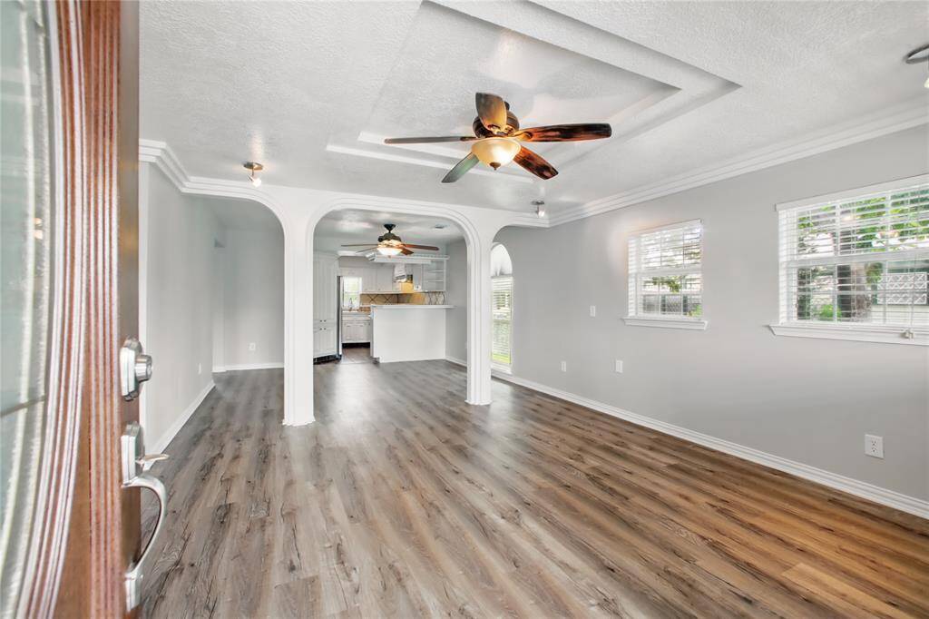 Open main living space elegantly appointed with arches, tray ceiling, crown molding.