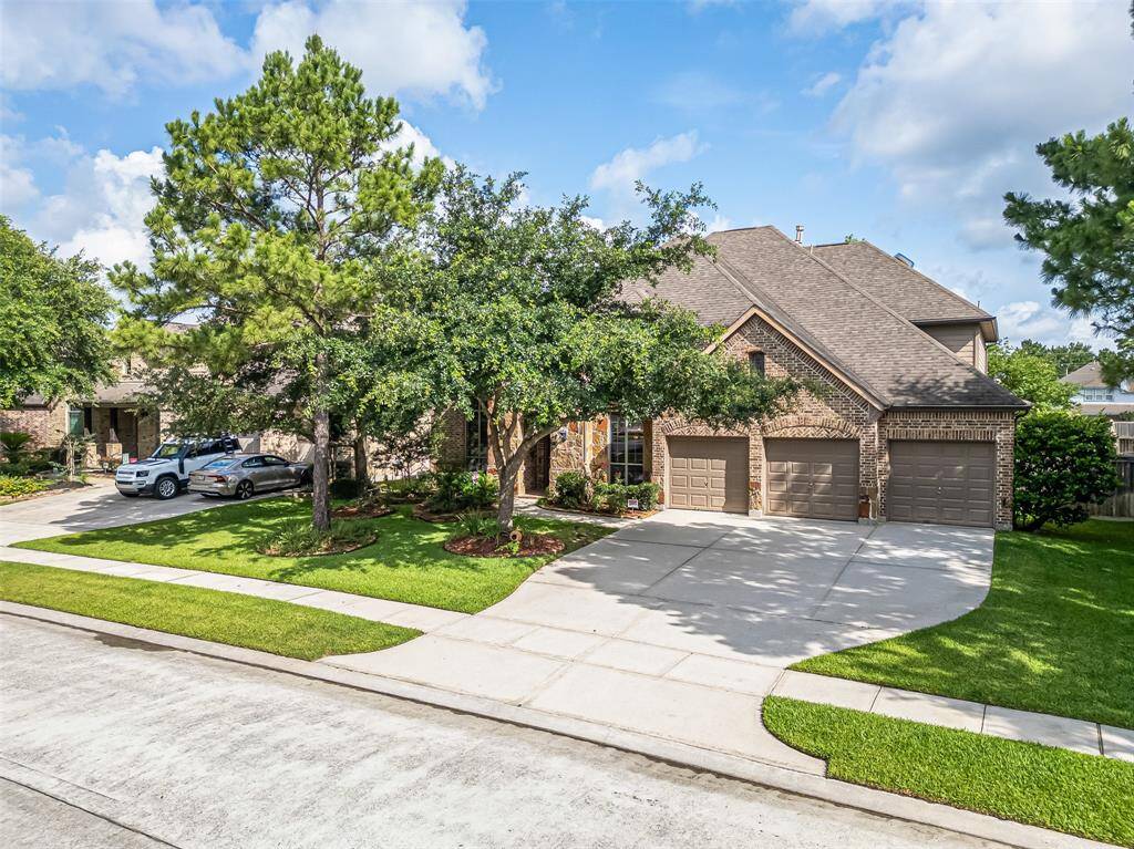 Charming stone and brick elevation with mature trees, lush landscaping, and a spacious 3-car garage welcome you home.