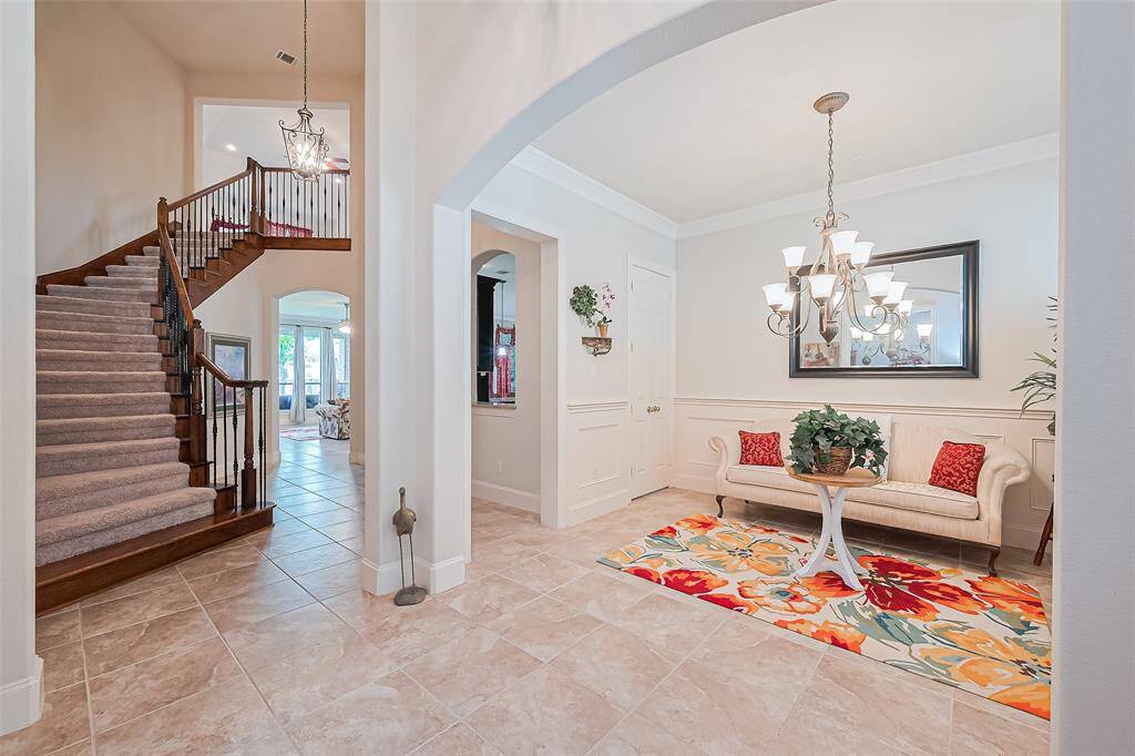Grand foyer with tile flooring, soring 20 ft high ceilings, wrought iron staircase and arched entryway creates a light-filled and elegant entrance.