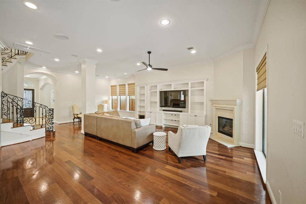 Serving as a focal point of the beautiful family room situated on the back of the home is a custom built-in entertainment center with flat screen TV included, display & bookshelves and cast stone gas log fireplace with mantel & hearth.