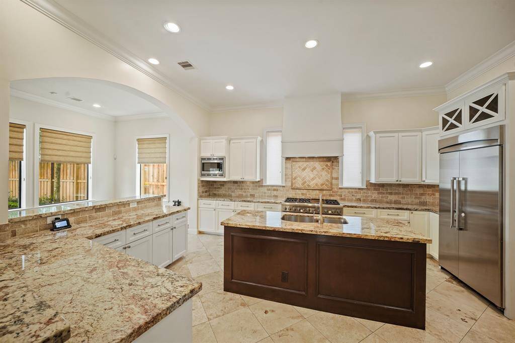 Stunningly designed, the gourmet kitchen with crown moulding, recessed lighting & diagonally-laid travertine tile flooring includes 42" painted cabinets with under-cabinet lighting highlighted by a travertine tiled back splash.