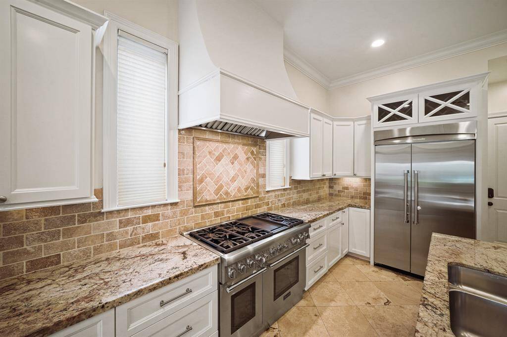 The Thermador stainless steel appliance package includes a commercial grade 6-burner gas range with griddle and double ovens accompanied by a vent hood with lighting, built-in double-door refrigerator with wine rack above, a built-in microwave oven and dishwasher. Included is a built-in under-counter wine/beverage fridge.