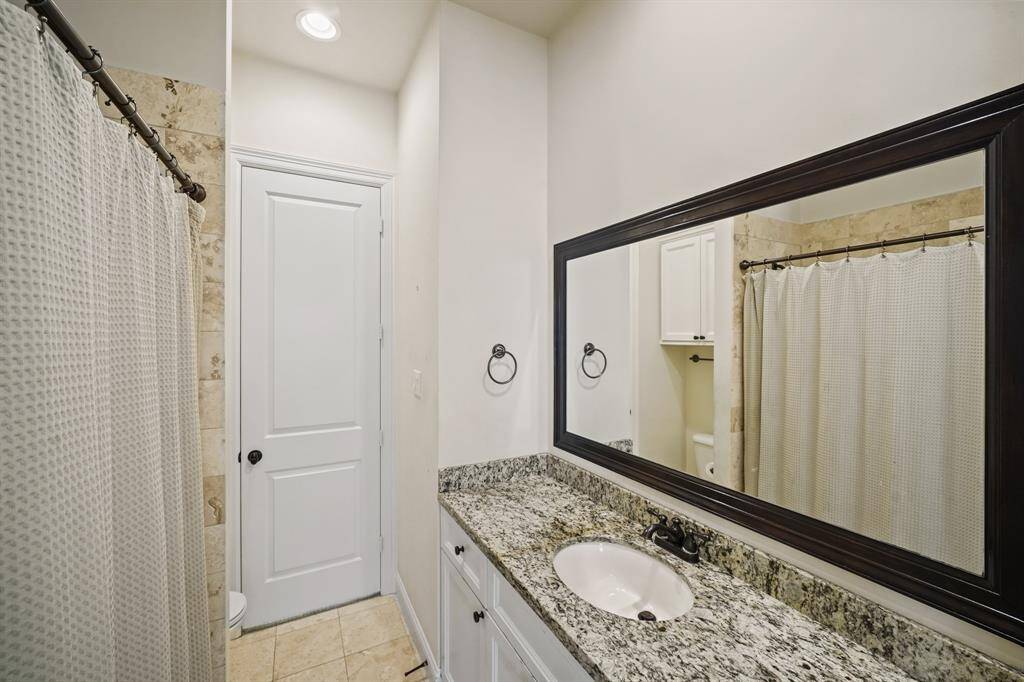 Situated between the second & third bedrooms is the home's second full bath with white painted cabinets supporting a granite counter top with an under-mount sink highlighted by a custom framed mirror and oil rubbed bronze plumbing & lighting fixtures. Just opposite the vanity is a travertine tile surrounded combination tub/shower and there is a linen storage closet located in the corridor just outside this full bath.