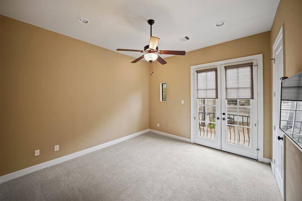 The fourth bedroom with en-suite bath has recessed lighting, ceiling fan with lighting, a walk-in wardrobe closet & beautiful patterned carpet. The French doors in the background open to a "Romeo & Juliet" wrought iron balcony overlooking the front of the home.