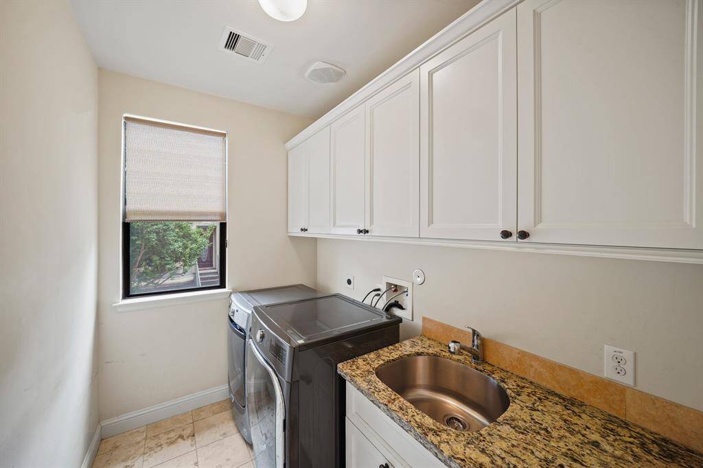 Located on the second level of the home, the utility room includes a window with window shade, plenty of upper & lower cabinet storage, a granite surfaced folding counter with a stainless steel under-mount utility sink & tile flooring. The full-size front loading washer & dryer will remain with the home.