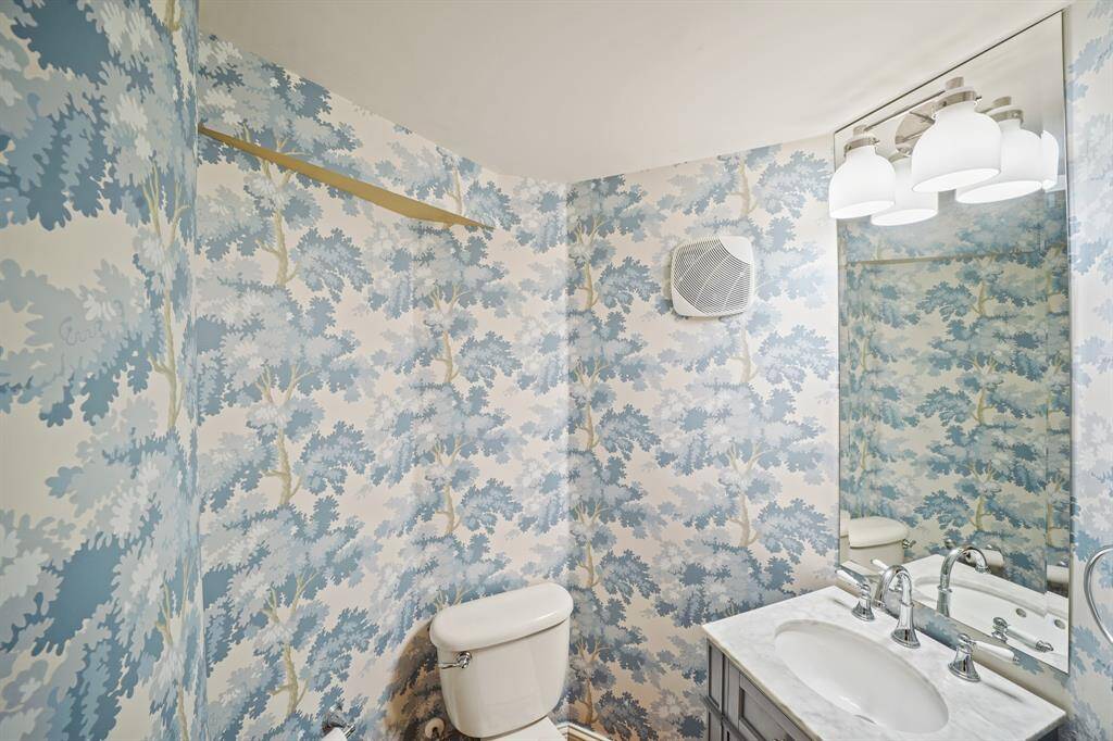 Convenient for guests, the first floor half bath includes a pedestal sink accompanied by a wall-mounted beveled mirror, polished silver plumbing and lighting fixtures & hardwood flooring.