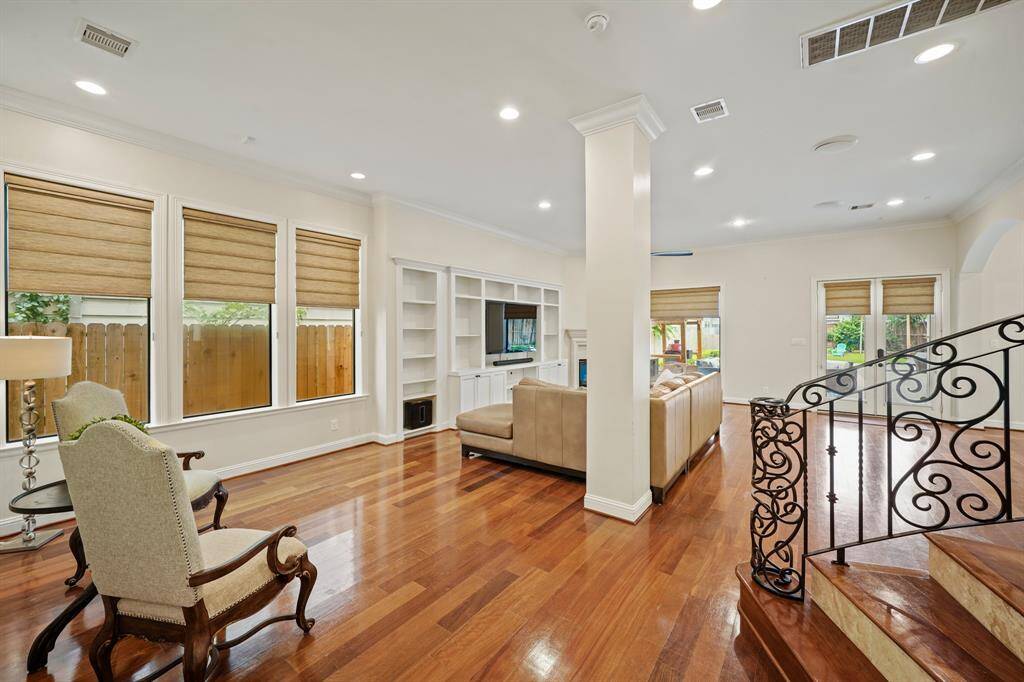 The first floor open living space features high ceilings, recessed lighting, crown moulding, arched openings to the  breakfast and kitchen along with hardwood floors. Decorative columns discretely divide the den & living room or use the entire space as one large family room. The sweeping ornate wrought iron staircase leads to the second & third levels of the home.
