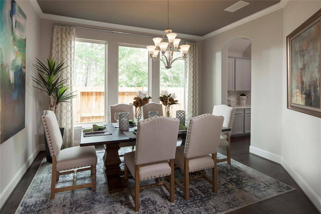 The elegant dining room is bathed in natural light from tall, expansive windows and offers seamless access to the kitchen through a convenient arched entryway.