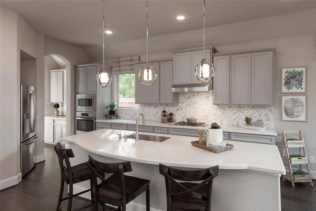 The gourmet kitchen is a chef’s dream, featuring a large center island, a breakfast bar for casual dining, and tall custom cabinets that offer abundant storage.