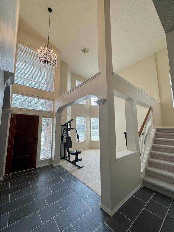 Step into this stunning entryway featuring soaring ceilings, a grand new chandelier, and large windows that flood the space with natural light. The formal living room sits just beyond the foyer, offering an elegant space for gathering. The newly updated tile flooring adds a sleek touch, complementing the home's sophisticated design.