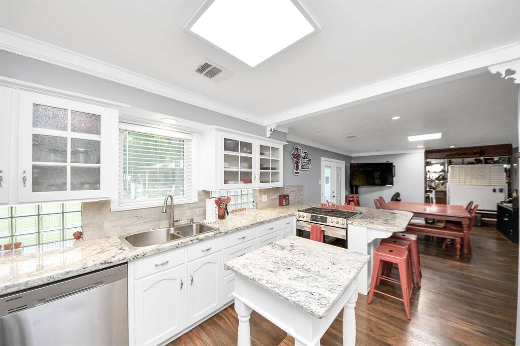 The kitchen features beautiful cabinetry, granite counters, a large breakfast bar, and lots of storage. The door leads to the large utility room.