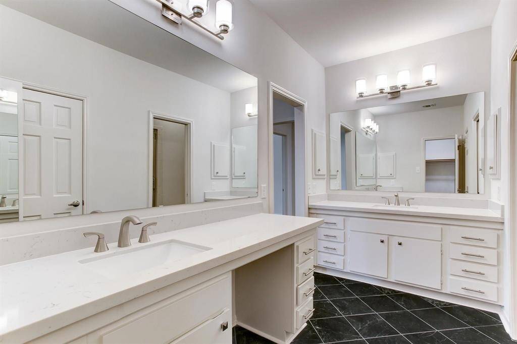Updated primary bath with quartz counter-tops, two separate vanities with under-mount sinks, updated hardware, and frame-less glass shower door to walk-in shower.