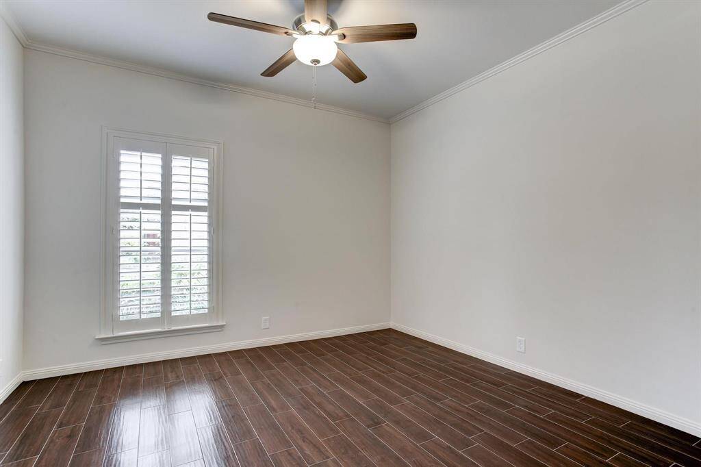 Generous sized secondary bedroom with wood-look porcelain tile floor, lighted ceiling fan and large window with plantation shutters.