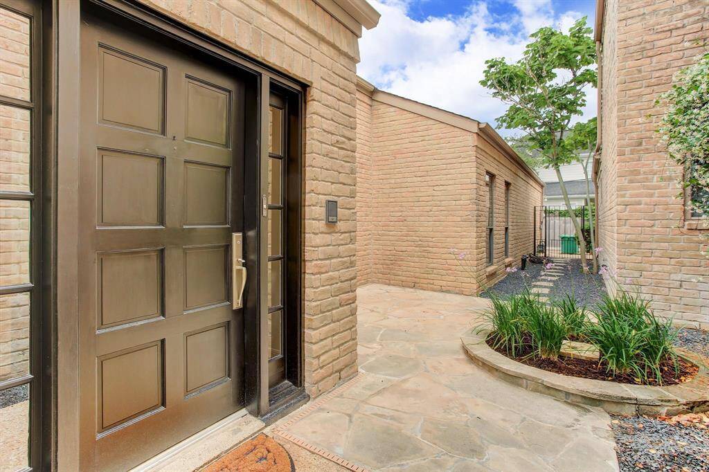 Handsome paneled wood door with side lights opens onto slate patio and private courtyard with planter. Walkway is gated on either end.