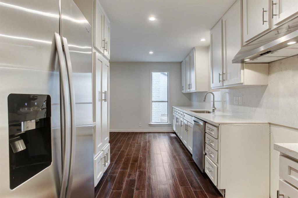 Another angle of kitchen looking toward substantial sized breakfast area with window overlooking sunroom. New stainless refrigerator features water and ice dispenser.