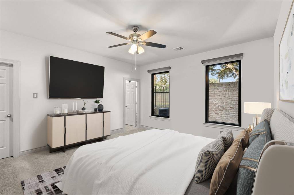 Discover the perfect retreat in this first-floor bedroom, featuring soft carpet underfoot, a private en-suite bathroom for ultimate convenience, and two windows adorned with elegant custom roller shades, creating a warm and inviting ambiance.