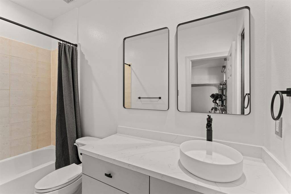 Step into this stylish bathroom featuring a sleek shower/tub combo, a quartz countertop, chic grey cabinets, and bold black hardware, blending modern elegance with everyday functionality.