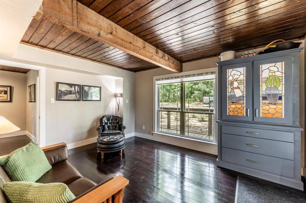 The den features large windows that look our toward the quiet neighborhood street.  The den also features a beautiful built in and lit cabinet with satin lever hardware.  The bottom drawers match the drawers in the kitchen and the top is designed around two antique stained glass pieces.  This room would make a fantastic second family area, a home office or a den. The door way to the left leads into the primary bedroom.