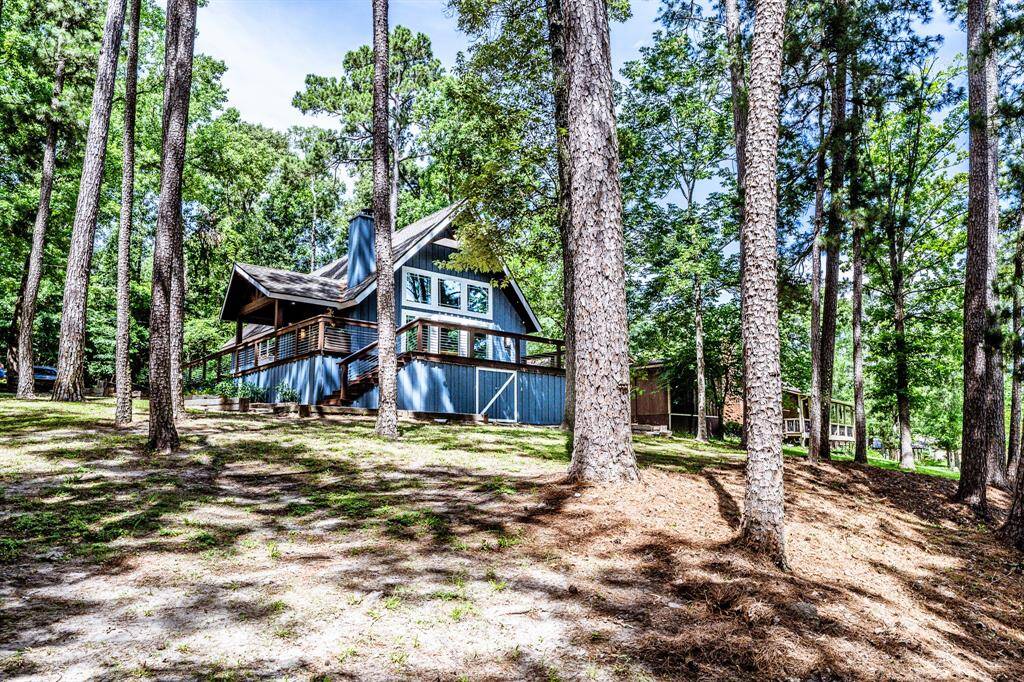 From water, looking up toward the back of the house. Mature trees abound.