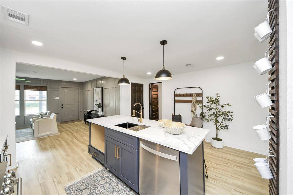The kitchen has pendant lighting over the island and overlooks the living room.