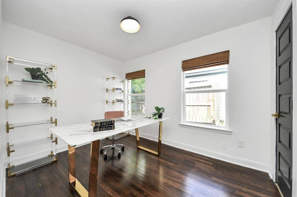 Third bedroom, currently used as a home office, features large windows and a modern lighting fixture.