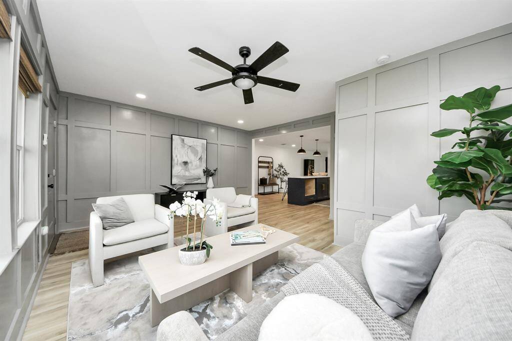 Living room features beautiful flooring, aceiling fan, recessed lighting, custom paint, and large windows.