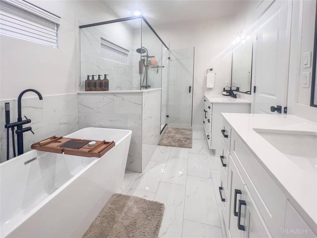 spacious primary bathroom with soaking tub, walk-in shower, double sink and linen closet