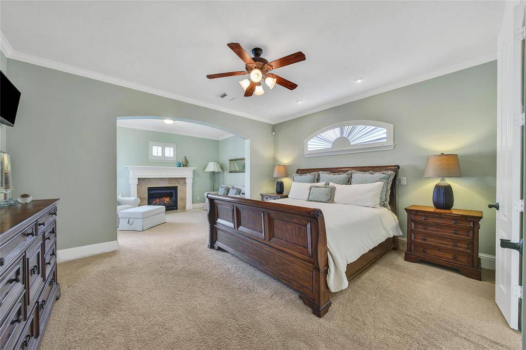 A large primary bedroom with a sitting area and private patio access offers a peaceful retreat, blending comfort and indoor-outdoor living.