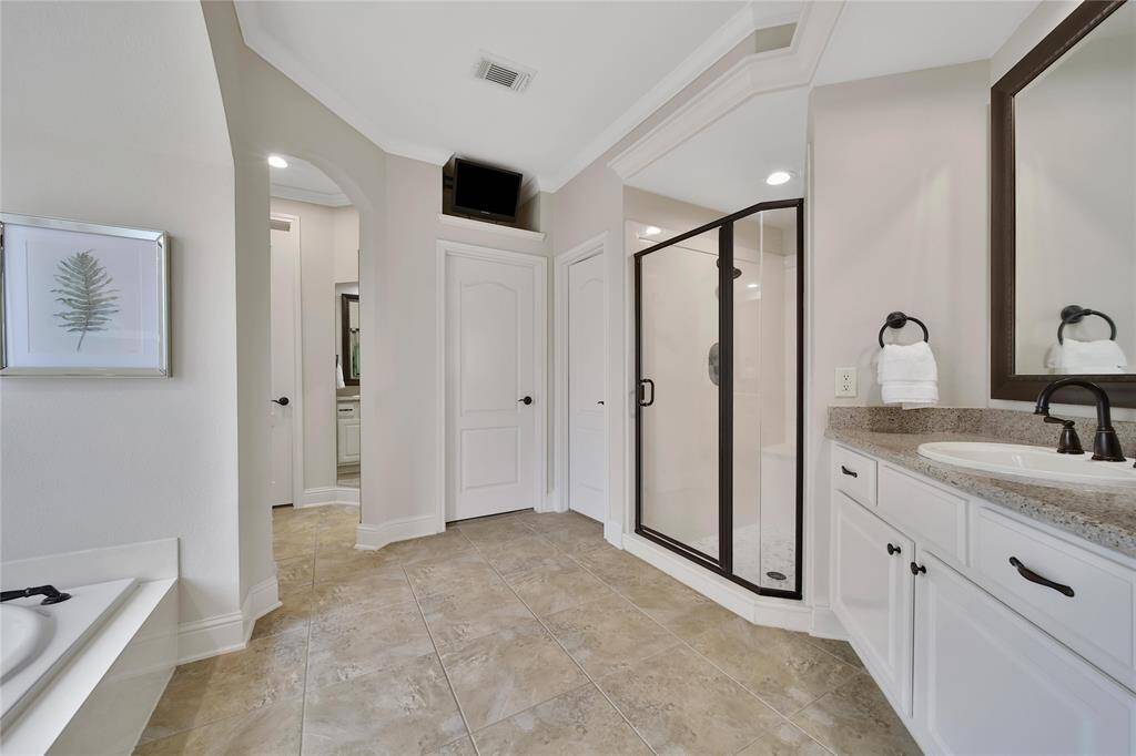 With plenty of room and dual vanities, two people can comfortably get ready at the same time without feeling crowded. The bathroom flows seamlessly into the primary closet, which features custom built-ins, a wall safe, and a convenient extra storage nook.
