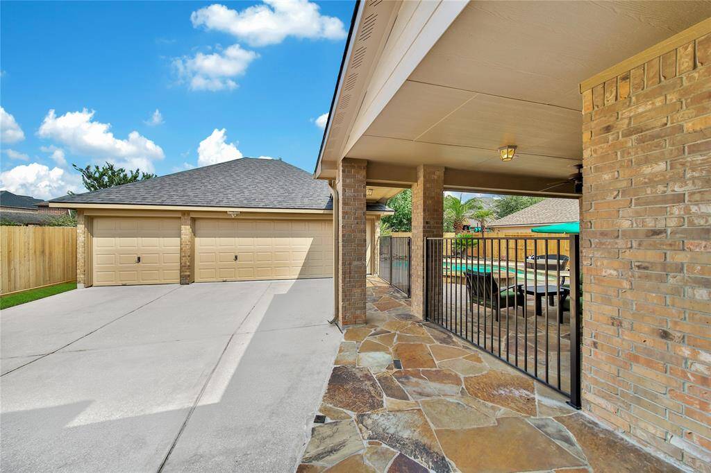 A true 3-car garage provides ample space for multiple vehicles, storage, and hobbies, offering both functionality and flexibility for modern living. An iron gate seperates the driveway from the backyard pool area.