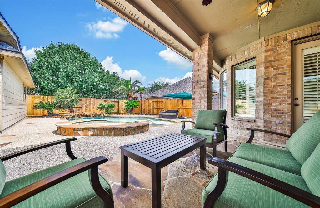 A covered patio overlooking the pool creates a perfect space for relaxing or entertaining outdoors, offering shade, comfort, and a seamless connection to the backyard oasis.